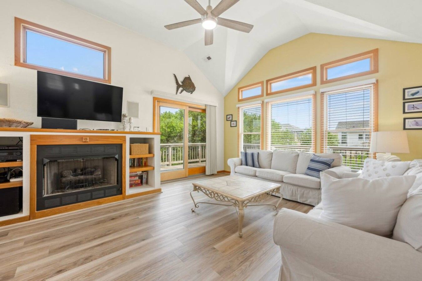A spacious living room with a fireplace, a television, and a ceiling fan.