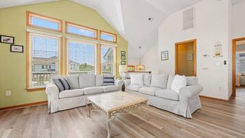 Ein geräumiges Wohnzimmer mit hohen Decken, großen Fenstern und Holzboden.