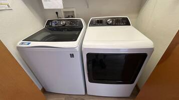 A laundry area with two washing machines and a sign advising against overloading.