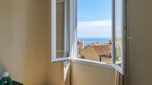 A room with a window overlooking a cityscape and the sea. - Elegant one-bedroom apartment with sea view at the gateway to Monaco (Beausoleil)