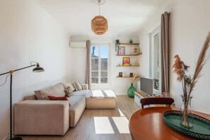 A modern living room with a sofa, a dining table, a lamp, and a hanging light fixture. - Bright 2-bedroom apartment with balcony in the heart of the city (Niza)