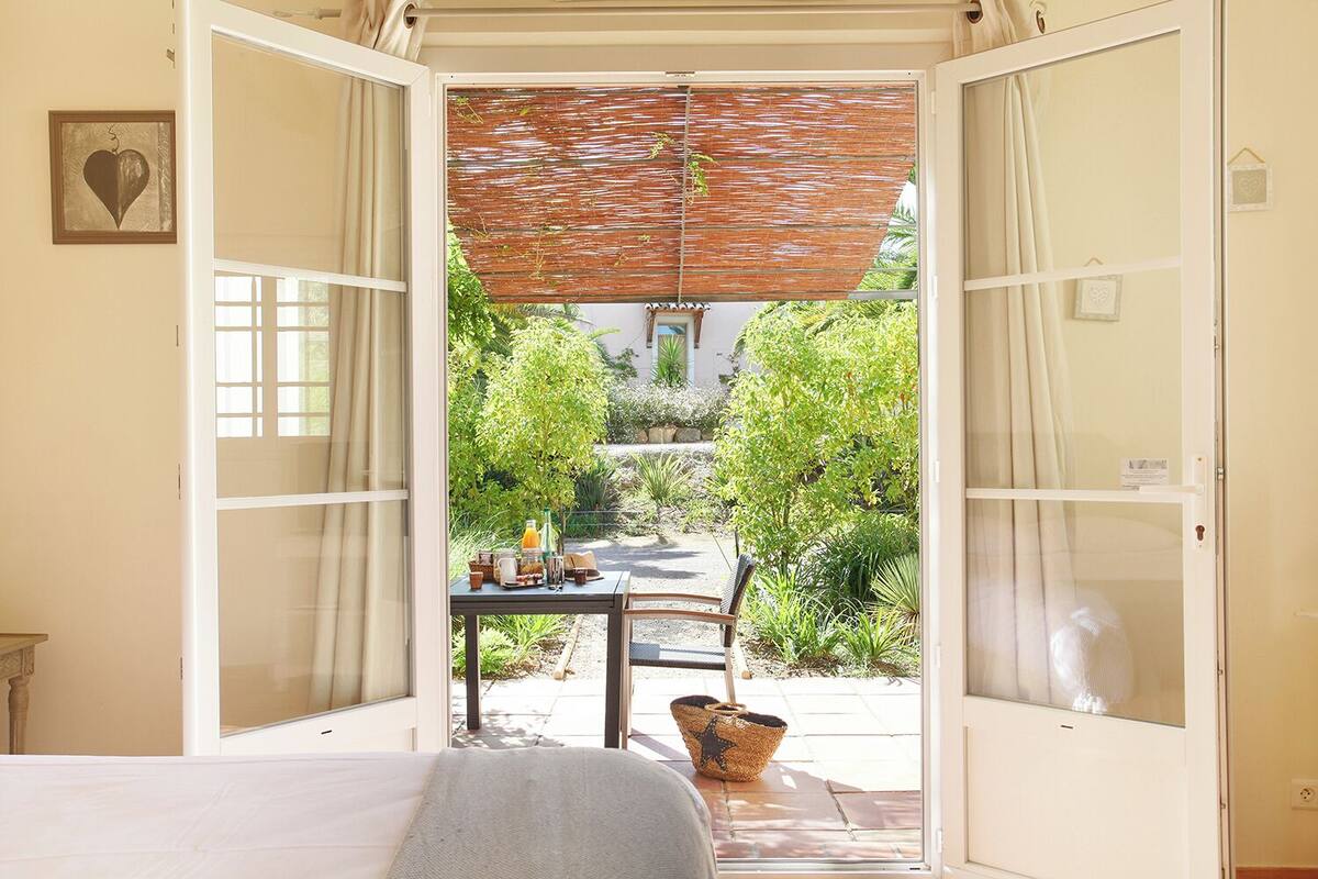 An open bedroom with a view of a garden.