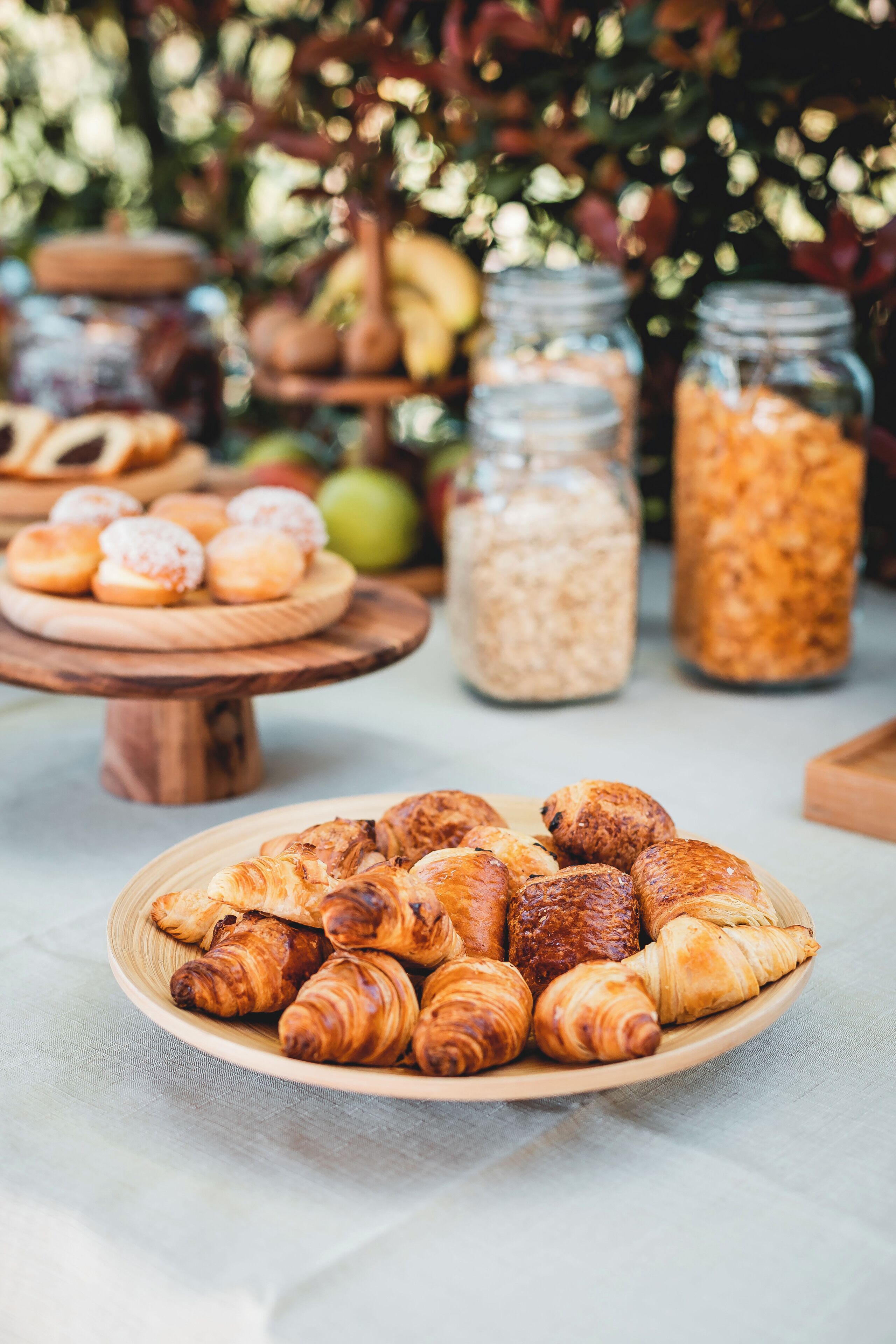 Et bord med forskellige bagværk, blandt andet croissanter og kager, samt glas med tilsyneladende korn eller frø.