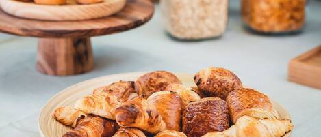 A table with various baked goods, including croissants and pastries, and jars of what appears to be grains or seeds.