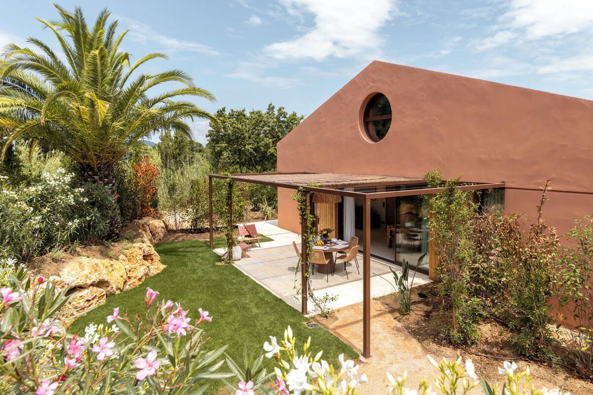 A modern house with a patio, a pergola, and a garden with various plants and flowers.