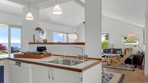 A modern kitchen with white cabinets, a wooden countertop, and a large window overlooking the ocean. - "Tobias" - 45m to the fjord by Interhome (Børkop)