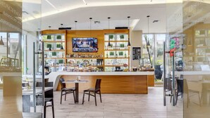 A bar area with a wooden counter, multiple shelves of bottles, a television screen, and a seating area with chairs. - Cozy Studio with Pool & Bay View Fitness Center (Hallandale Beach)