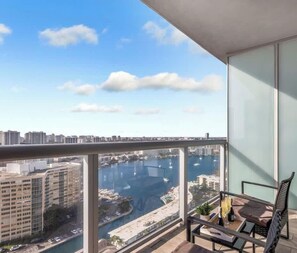 A balcony with a city view, a chair, and a railing.
