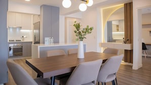 A modern kitchen with a central island, a dining area with a wooden table and chairs, and a pendant light fixture. - w* | Amazing 3BR w/ Balcony in Miraflores (Miraflores)