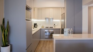 A modern kitchen with grey cabinets, a built-in oven, and a coffee maker. - w* | Amazing 3BR w/ Balcony in Miraflores (Miraflores)