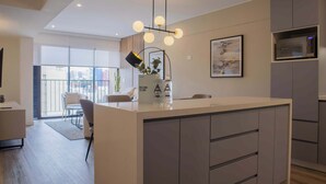 A modern kitchen with a central island, a hanging light fixture, and a microwave built into the cabinetry. - w* | Amazing 3BR w/ Balcony in Miraflores (Miraflores)