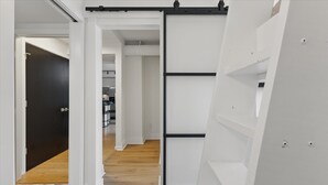 A hallway with a sliding door, white walls, and a kitchen in the background. - Modern Flat in the Heart of Indianapolis (Indianapolis)