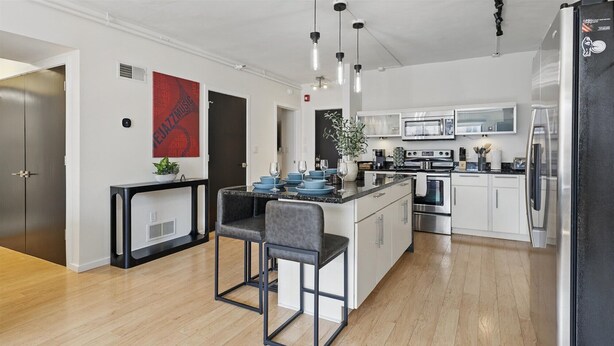 A modern kitchen with a central island, stainless steel appliances, and a bar area with stools. - Modern Flat in the Heart of Indianapolis (Indianapolis)