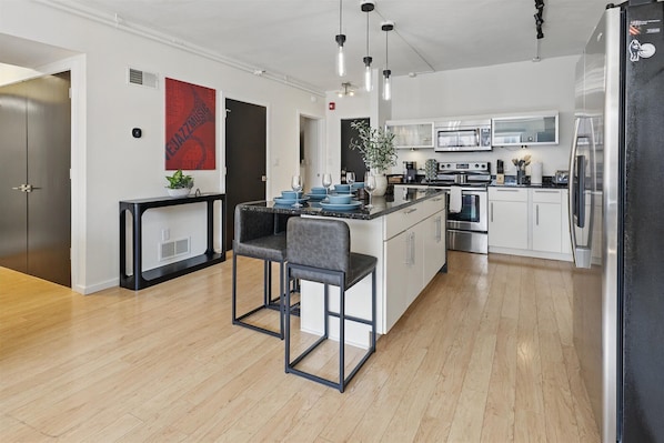 A modern kitchen with a central island, stainless steel appliances, and a bar area with stools.