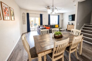 A dining area with a wooden table and chairs, a ceiling fan, and a staircase leading to another level.
