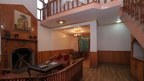 Uma área de refeições com mesa e cadeiras de madeira, lareira e escada com guarda-corpos de madeira.