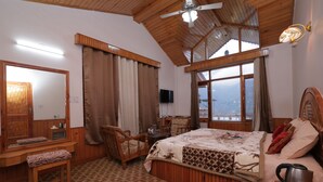 Quarto com decoração em madeira, uma cama, um banco, uma TV e janela com vista.