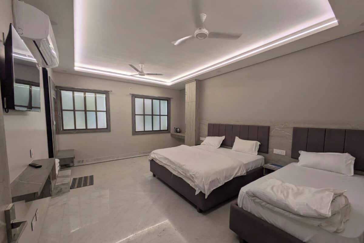 A modern hotel room with two beds, a ceiling fan, and a large window.