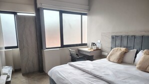 Una habitación de hotel con una cama grande, un escritorio, una silla y una ventana con vistas.