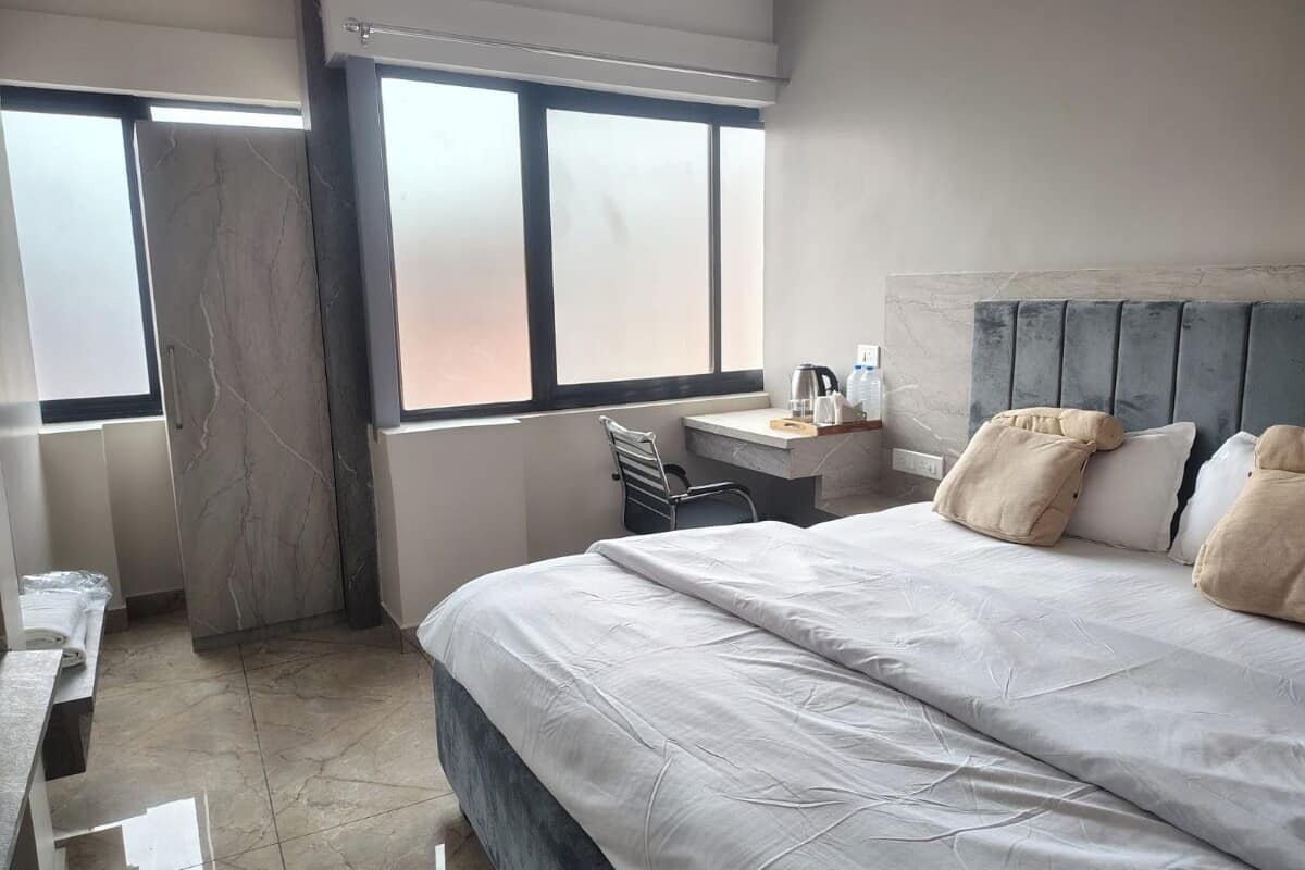 A hotel room with a large bed, a desk, a chair, and a window with a view.