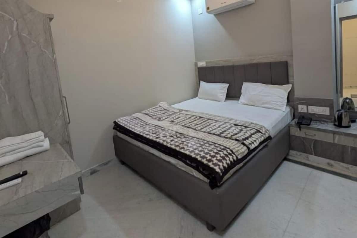 A modern bedroom with a bed, a ceiling fan, an air conditioning unit, and a marble-tiled floor.
