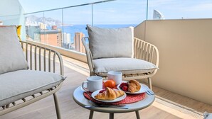 A balcony with two chairs, a table with croissants, a coffee cup, and an orange. - BENIDORM BEACH magic apartment (Benidorm)