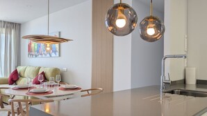 A modern kitchen with a central island, pendant lighting, and a dining area with chairs and a table set for two. - BENIDORM BEACH magic apartment (Benidorm)