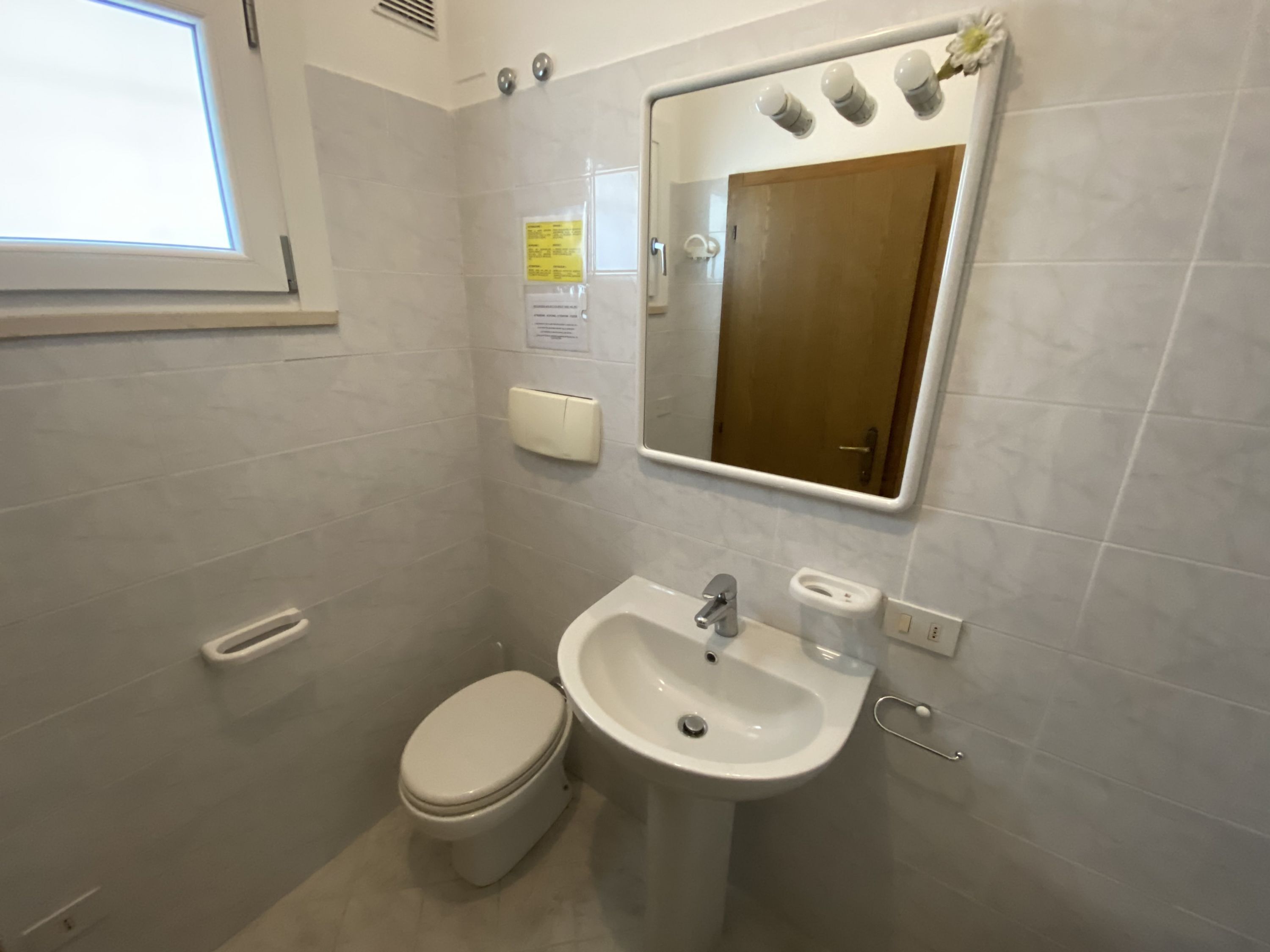 Kylpyhuone, jossa on wc, pesuallas ja peili.