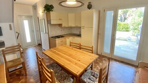 A modern kitchen with white cabinets, a wooden dining table, and a large window. - Cometa 3 in Bibione With 2 Bedrooms and 2 Bathrooms (San Michele al Tagliamento)