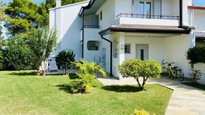 A two-story house with a balcony, a small garden, and a bicycle parked outside. - Cometa 3 in Bibione With 2 Bedrooms and 2 Bathrooms (San Michele al Tagliamento)