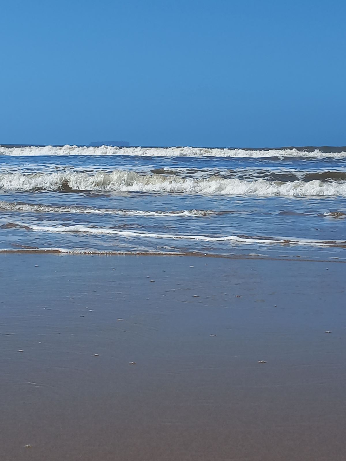 Une plage avec des vagues et un ciel dégagé.