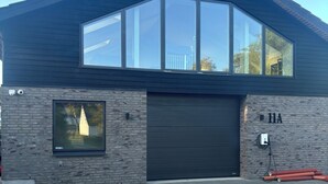 A modern building with a large garage door, a small window, and a number '11A' on the wall. - 6 person modern apartment with style and comfort (Lejre)