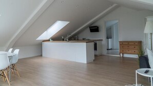 A modern loft apartment with a kitchen island, dining area, and a TV mounted on the wall. - 6 person modern apartment with style and comfort (Lejre)