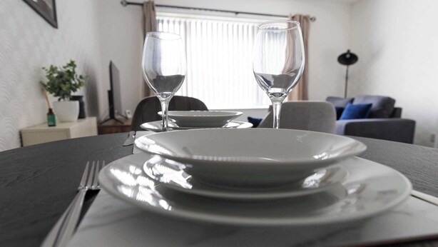 A dining table set with plates, cutlery, and two wine glasses.