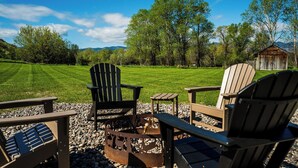 A patio with Adirondack chairs, a small table, and a fire pit.