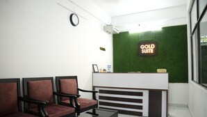 A reception area with a reception desk, a clock, and a green wall with a 'Gold Suite' sign. - Goldsuite (Kanayannur)