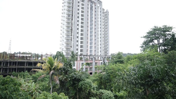 A high-rise building with multiple floors, surrounded by dense greenery. - Goldsuite (Kanayannur)