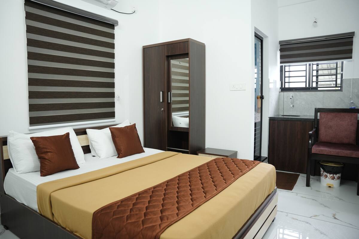 A hotel room with a bed, a wardrobe, a sink, and a chair.