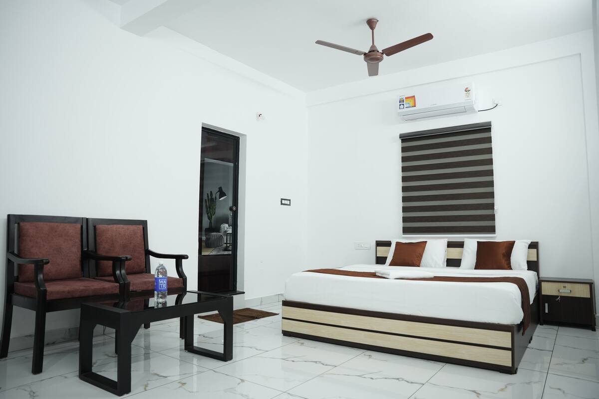A modern hotel room with a bed, a sofa, a coffee table, and a ceiling fan.