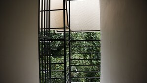 A balcony with metal railings and a view of greenery outside. - Goldsuite (Kanayannur)