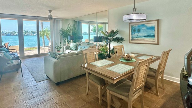 A spacious living area with a dining table, chairs, and a view of the ocean.