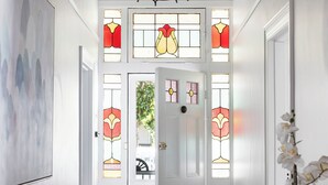 A hallway with white walls, a wooden floor, a black chandelier, and a door with stained glass windows. - Brighton Pool Paradise: Designer 3BR Retreat Near Beach & Café Culture (Brighton)