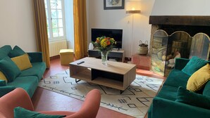 Una sala de estar con sofás verdes, una mesa de centro de madera, un televisor y una chimenea.