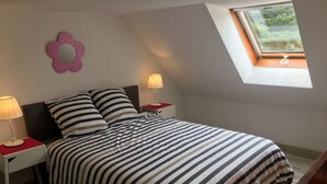 A bedroom with a bed, two bedside tables with lamps, a window, and a decorative flower on the wall. - Sea view apartment 100m from the beach (Saint-Nic)