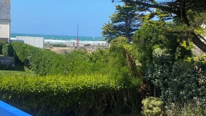 A coastal view with a clear sky, a grassy area, and a blue railing. - Sea view apartment 100m from the beach (Saint-Nic)