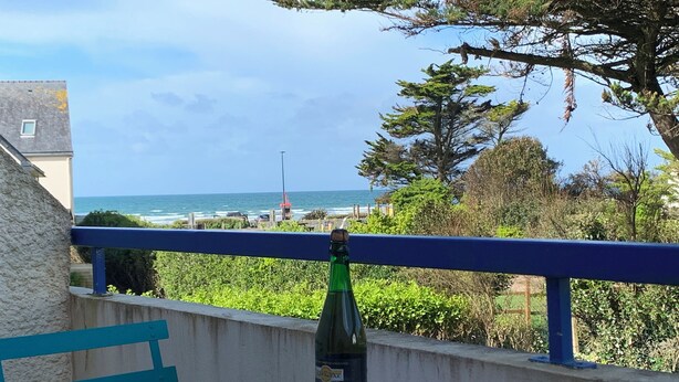 A balcony with a table set for two, overlooking a coastal view with a bottle of wine and two cups. - Sea view apartment 100m from the beach (Saint-Nic)