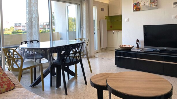 Un salon moderne comprenant un coin repas, un téléviseur à écran plat et une grande fenêtre donnant sur l’extérieur.