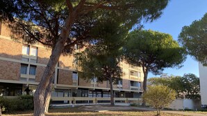 Un immeuble à plusieurs étages, doté d’une façade en briques, de grandes fenêtres et d’une cour intérieure avec des arbres et de l’herbe.