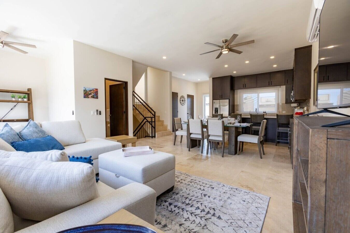 A modern living room with a sofa, ottoman, and a dining area with chairs and a table.