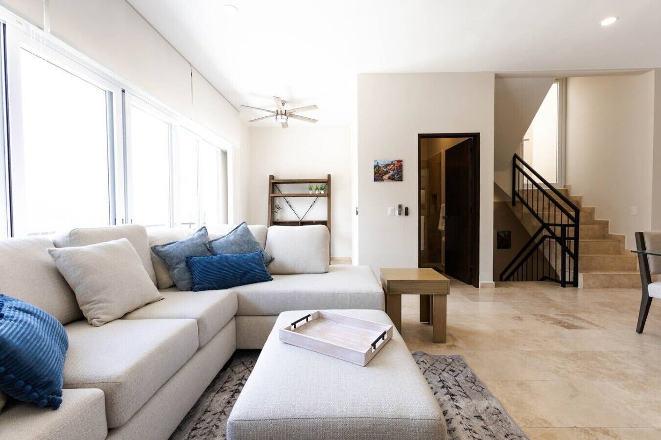 Ein modernes Wohnzimmer mit einem Ecksofa, einem kleinen Tisch und einer Treppe.